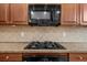 A kitchen with a cooktop and microwave, complemented by a tiled backsplash and ample cabinetry at 2988 Rivergreen Se Ln, Atlanta, GA 30339