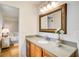 Well-lit bathroom featuring a wood vanity, granite countertop, decorative mirror, and stylish light fixture at 4140 Candler Lake West Ne, Atlanta, GA 30319
