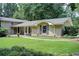 Landscaped front yard of a charming house with large lawn and mature trees in a serene, wooded setting at 4140 Candler Lake West Ne, Atlanta, GA 30319