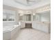 Bright bathroom featuring a garden tub, white tile flooring, ample counter space, and a large decorative window at 1250 Parkview Nw Ln, Kennesaw, GA 30152