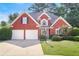 Charming red brick home featuring a two-car garage, manicured lawn, and lush landscaping at 1250 Parkview Nw Ln, Kennesaw, GA 30152