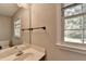 The powder room features a single sink, a mirror, neutral walls, a window, and a towel bar at 1592 Walkway Ct, Lilburn, GA 30047