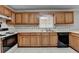Traditional kitchen features wooden cabinets, a double basin sink beneath a window, and white countertops at 1592 Walkway Ct, Lilburn, GA 30047