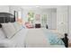 Bright bedroom with a dark wooden bed frame, many windows, and doors with white trim at 100 Parkerwood Way, Alpharetta, GA 30022