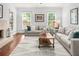 Cozy living room filled with natural light, plush sofas, fireplace, and hardwood floors at 100 Parkerwood Way, Alpharetta, GA 30022