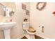 Charming powder room with pedestal sink, wood-look floors and decorative wall art at 10044 Cormac St, Jonesboro, GA 30238