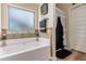 Relaxing bathroom featuring a soaking tub, neutral tile and frosted window at 10044 Cormac St, Jonesboro, GA 30238