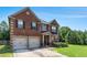 Beautiful red brick home with a two-car garage, a manicured lawn, and mature trees providing ample shade at 10044 Cormac St, Jonesboro, GA 30238