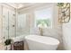 Bright bathroom featuring a modern tub, frameless shower, and marble tile at 4395 Capstone Court, Roswell, GA 30075