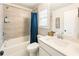 Bright bathroom with a shower-tub combo featuring tile surround and modern vanity with solid surface countertops at 4395 Capstone Court, Roswell, GA 30075