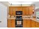 Well-lit kitchen featuring oak cabinetry, granite countertops, black appliances, and decorative accents at 17 Sassafras Ne Trl, Cartersville, GA 30121