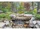 Charming waterfall feature surrounded by lush greenery and natural stones creates a tranquil backyard oasis at 218 Floral Valley Dr, Woodstock, GA 30188