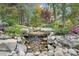 Picturesque backyard waterfall feature with lush landscaping and natural stone accents creates a tranquil oasis at 218 Floral Valley Dr, Woodstock, GA 30188