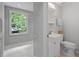 Bright bathroom featuring a vanity, toilet, and a window offering serene views of the surrounding greenery at 9470 Hillside Dr, Roswell, GA 30076