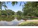Beautiful lake view with green grass, trees, calm water, and a home in the distance at 9470 Hillside Dr, Roswell, GA 30076