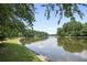 Lake view with lush green trees and calm water on a sunny day at 9470 Hillside Dr, Roswell, GA 30076