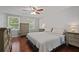 Comfortable main bedroom with wood floors, matching dressers, ceiling fan, and large windows at 9470 Hillside Dr, Roswell, GA 30076
