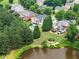 Aerial view featuring several homes with manicured lawns and backyard pools backing onto a peaceful lake at 4526 Meadow Club Dr, Suwanee, GA 30024