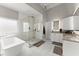 Bright bathroom with a modern soaking tub, glass enclosed shower and white cabinets with a gray counter top at 4526 Meadow Club Dr, Suwanee, GA 30024