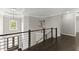 Upstairs hallway with dark hardwood floors, metal railings, and modern lighting fixtures at 4526 Meadow Club Dr, Suwanee, GA 30024