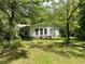 Exterior view of the home featuring large windows and a large yard surrounded by mature trees at 4701 Cleveland Rd, Lithonia, GA 30038