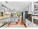 Open-concept kitchen boasts white cabinetry, stainless steel appliances, granite countertops, and hardwood floors at 119 Castlewood Rd, Tyrone, GA 30290