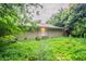 View of the backyard featuring a brick home exterior surrounded by mature trees and lush ground cover at 3409 Hyland Dr, Decatur, GA 30032