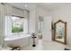 Luxury bathroom featuring a soaking tub, large windows with sheer curtains, and stylish fixtures at 1952 Sugarstone Dr, Lawrenceville, GA 30043