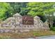 Stone community entrance sign that reads Sugarloaf Springs with mature shade trees surrounding it at 1952 Sugarstone Dr, Lawrenceville, GA 30043