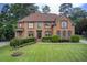 Stately brick home featuring manicured lawn, mature trees, and traditional architectural details at 1952 Sugarstone Dr, Lawrenceville, GA 30043