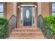 Elegant front porch with brick steps, black railings, and an oval glass front door at 1952 Sugarstone Dr, Lawrenceville, GA 30043