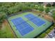 Aerial view of community tennis courts with blue playing surface, lights, and green surroundings at 1952 Sugarstone Dr, Lawrenceville, GA 30043