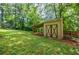 View of the backyard featuring green grass, trees, and a storage shed with double doors at 407 Doris Dr, Woodstock, GA 30188