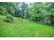 Lush backyard featuring green grass, mature trees, and a shed, offering a serene outdoor space at 407 Doris Dr, Woodstock, GA 30188
