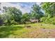 Large backyard featuring mature trees, green grass, a storage shed, and a garden plot at 407 Doris Dr, Woodstock, GA 30188