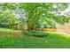 Backyard view shows the shed, beautiful mature trees, green grass, and landscaping at 407 Doris Dr, Woodstock, GA 30188