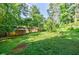 Expansive backyard featuring a shed, green grass, and mature trees, offering privacy and space at 407 Doris Dr, Woodstock, GA 30188
