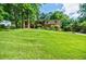 Exterior home view featuring a sprawling front lawn, mature trees, and a welcoming facade at 407 Doris Dr, Woodstock, GA 30188