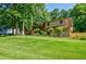 Exterior view showcasing the home with a lush green lawn, mature trees, and a charming residential street at 407 Doris Dr, Woodstock, GA 30188