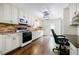 Well-equipped kitchen with modern appliances, white cabinets, brick backsplash, and wood flooring at 407 Doris Dr, Woodstock, GA 30188