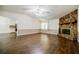 Open-concept living room with wood floors, a stone fireplace, and seamless access to the adjacent kitchen at 407 Doris Dr, Woodstock, GA 30188