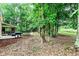 Side view of the backyard featuring outdoor seating and a grill, with a wooded area in the background at 135 Crimson Rdg, Tyrone, GA 30290