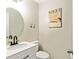 Half bath with a white vanity, round mirror, toilet, and modern decor at 135 Crimson Rdg, Tyrone, GA 30290