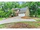 View of the rear and driveway side of the home showcasing landscaping and wooded lot at 135 Crimson Rdg, Tyrone, GA 30290