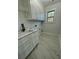 Laundry room featuring white cabinets, a sink with a black faucet, and marble-look tile at 3499 Lake Mill Rd, Buford, GA 30519