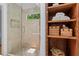 Clean and modern bathroom with glass shower and built-in wood shelves for towels and baskets at 970 Pine Grove Pointe Dr, Roswell, GA 30075