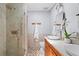Modern bathroom featuring glass shower, double vessel sinks, wood cabinets, and stone tile accents at 970 Pine Grove Pointe Dr, Roswell, GA 30075