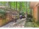 Stone patio features a grill, seating area, and retaining wall surrounded by trees at 970 Pine Grove Pointe Dr, Roswell, GA 30075