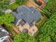 High-angle aerial shot displaying the roof, deck, landscaping, and the home nestled among green trees at 9975 Groomsbridge Rd, Johns Creek, GA 30022