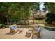 Spacious deck area with wicker patio furniture, overlooking a lush green lawn and wooded backyard at 9975 Groomsbridge Rd, Johns Creek, GA 30022